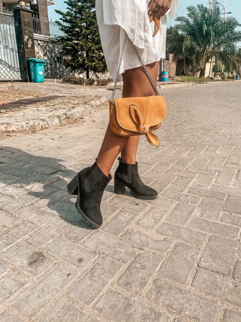 Iruoma Osonwa with a bag and pair of shoes creating content for social media