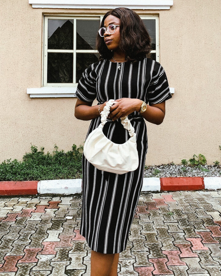 Blogger Iruoma in a dress with her white handbag posing